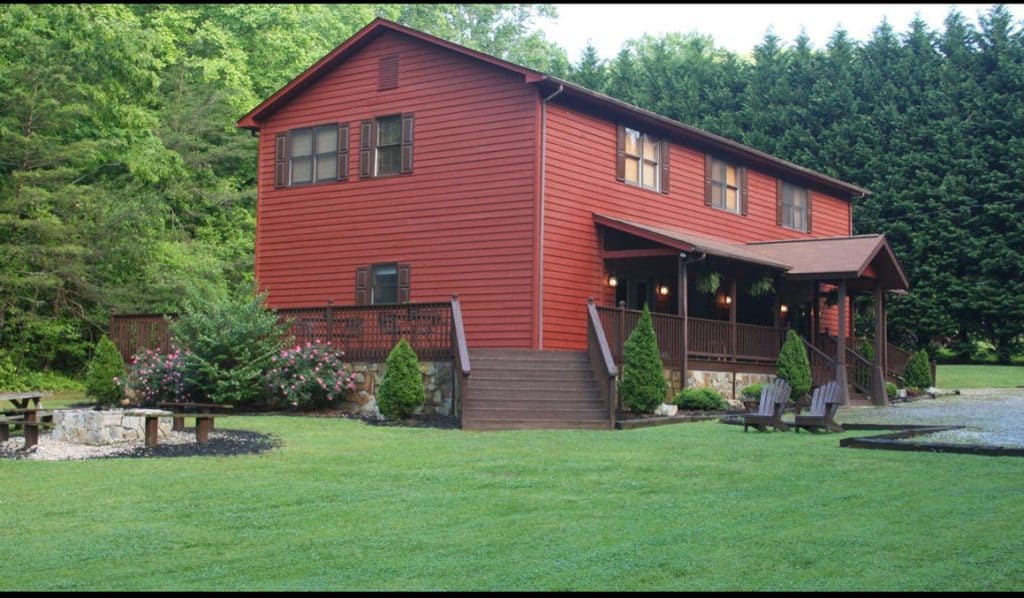 Red cabin with a spacious deck surrounded by lush greenery.